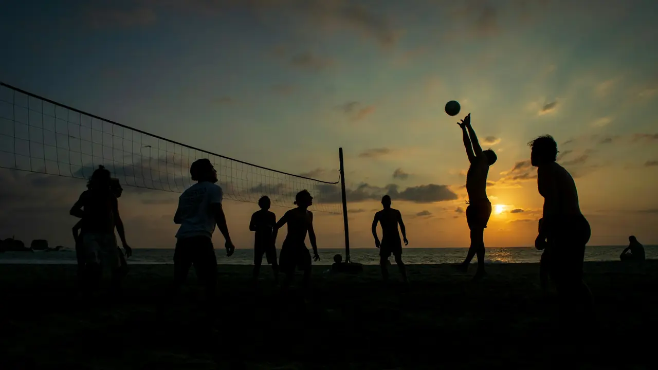 Silhuetas de pessoas jogando vôlei na praia ao entardecer
