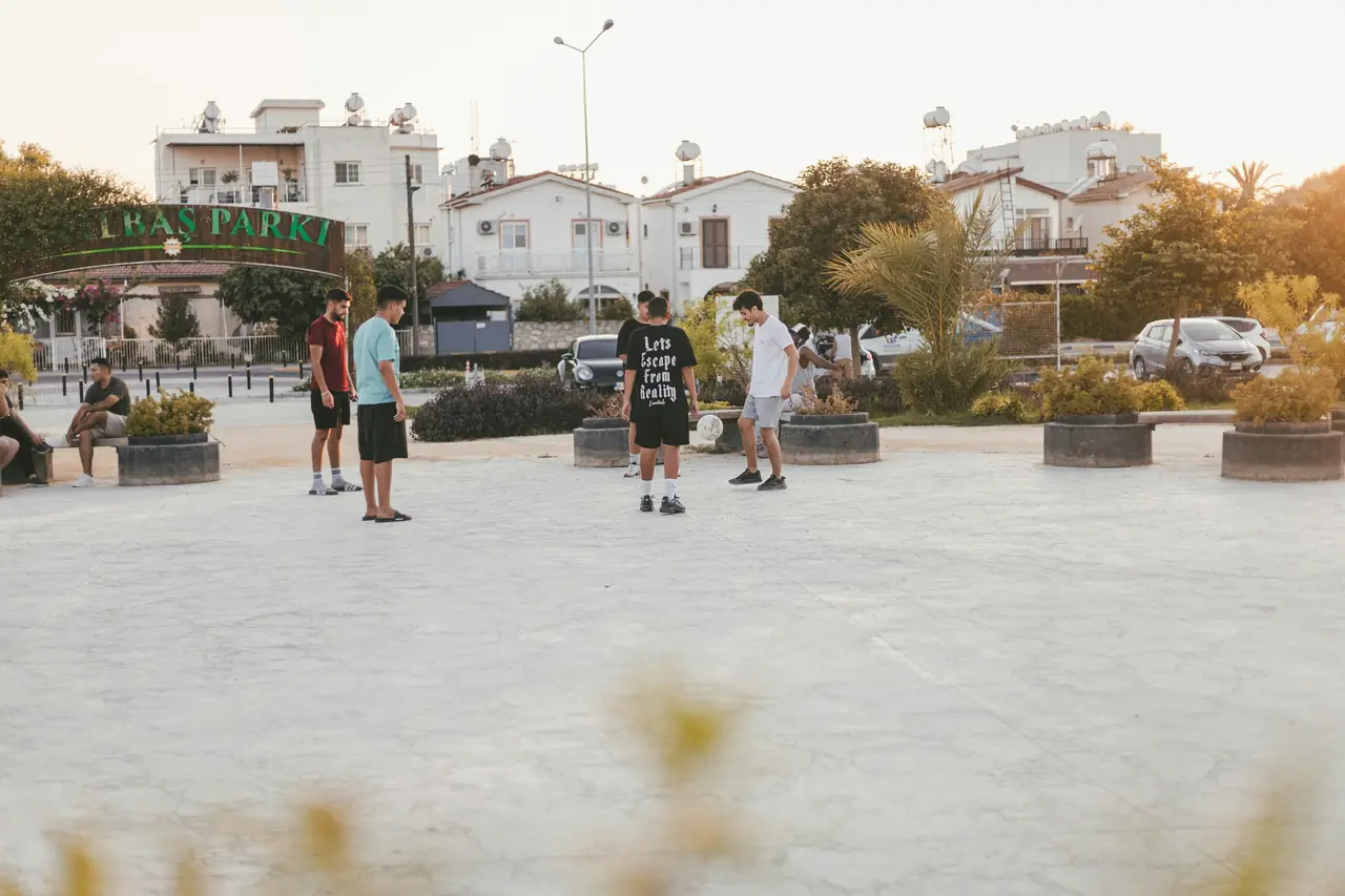 Young people kicking a ball around in a town square in the late afternoon